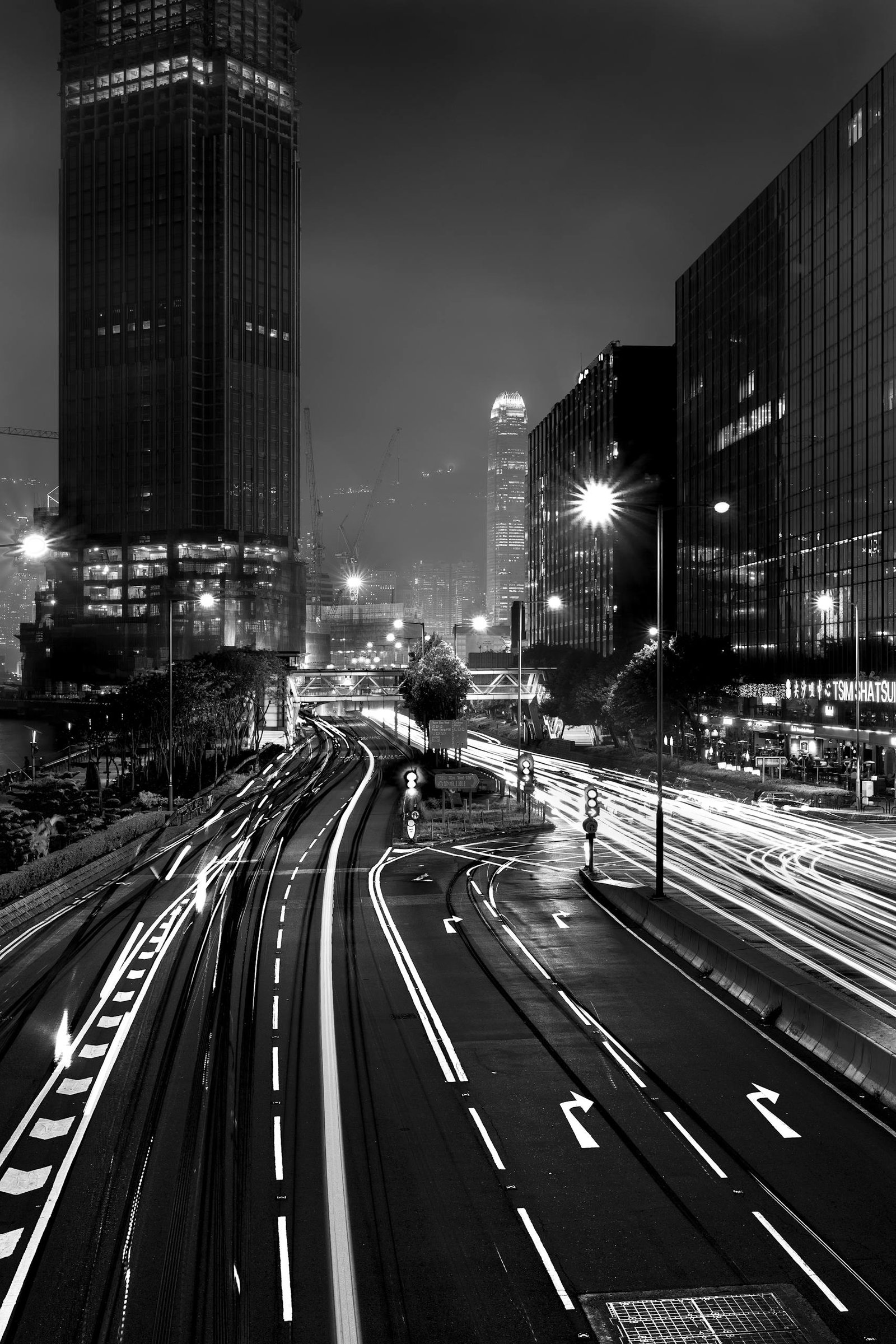 Captivating black and white cityscape showcasing light trails on urban roads at night.